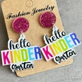 Macro view of acrylic teacher earrings with pink glitter and colorful Kindergarten text - Kindergarten (Hello Kindergarten)