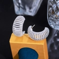 Macro shot of silver C-shaped hoop earrings with sparkling white zircons on a stand - White (E0595) / White