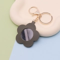 Detail of flower shaped green faux leather keychain with a small circular mirror and gold clasp - Flower Army Green