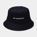 Primo piano dettagliato del ricamo bianco NOT INTERESTED su un cappello a secchiello nero - M (56-58cm) / Blu navy