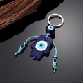Hamsa-Hand Schlüsselanhänger mit blauem Evil Eye Glasanhänger und Quasten auf schwarzem Grund - Glasperle Hamsa