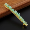 Macro shot of green crystal stones hand-wired on a golden hair pin with wood background - Green Aventurine + Gold Clip