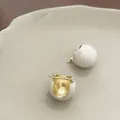 Détail de créoles de luxe en émail crème avec texture brossée et accents dorés - Boucles d'Oreilles Boules Émail Rétro - Blanc