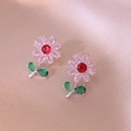 Vista macro di orecchini a fiore con zirconi rosa e foglie verdi su seta rosa - Orecchini A Fiore Colorati (Rosa/Verde)