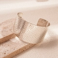 Macro-opname van zilveren brede armband met gehamerde textuur op stenen basis - Zilveren Gehamerd Gevlekte Stijl