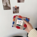 Close-up of mini knitted storage bag with colorful tufts and sozakka logo label - Lipstick Pouch
