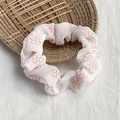 White floral scrunchie with orange flower prints on a woven tray surface - White with Pink Flowers