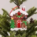 Christmas gingerbread house ornament with a red scarf gingerbread man hanging on a tree - Gingerbread House Style I
