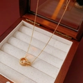 Dettaglio ciondolo a doppio anello dorato con cristalli su una scatola di legno vintage - Doppio Anello Intrecciato con Diamanti Oro (23#)
