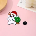 Broche chat de Noël en émail avec bonnet de Père Noël et sac cadeau vert sur fond rose - Chat Père Noël
