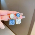 Détail de boucles d'oreilles fleurs en résine bleue avec bordure dorée - Épissage Ovale/Carré Irrégulier / Bleu