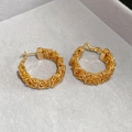 Macro shot of gold-plated woven texture C-shape hoop earrings on a velvet display stand - Gold