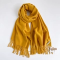 Sciarpa gialla morbida effetto cashmere con nappe su uno sfondo bianco pulito - Giallo zenzero