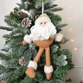 Plush Santa Claus ornament hanging on a Christmas tree branch with warm festive lights - Santa Claus