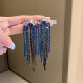 Dettaglio di orecchini pendenti con cristalli blu sfumati e nappe mostrati a mano - Stile 16 Perno in Argento Nappa a Forma di U Blu