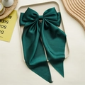 Détail d'un grand nœud papillon en satin vert foncé avec rubans sur un plateau crème - Vert Foncé