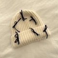 Beige gebreide muts met zwarte fluwelen strikken in een minimalistische bovenaanzicht - Wit