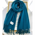 Peacock blue cashmere scarf with fringe edges and brand label on white table - Peacock Blue