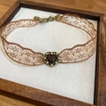 Detailed macro view of vintage lace choker with a bronze heart pendant in a wooden frame - Red Heart Brown Lace