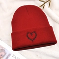 Detalle del gorro rojo de punto con bordado de corazón negro sobre fondo de peluche - Talla única / Rojo