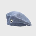 Close-up of a blue knitted beret featuring a black and white P letter patch detail - Fog Blue