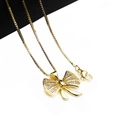 Close-up of golden bow pendant with sparkling cubic zirconia on a sturdy box chain - Pendant And Necklace (4)