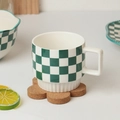 Detail einer grün-weiß karierten Keramiktasse mit quadratischem Griff auf Korkuntersetzer - Grüne Schachbrett Quadratischer Griff