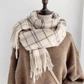 Close-up of beige plaid cashmere scarf featuring soft texture and fringe tassel details - Cream