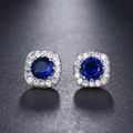 Macro view of silver round stud earrings featuring blue sapphire center stone and zircon halo - Dark Blue