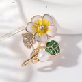 Broche de flores con base dorada, pétalos esmaltados, pedrería y perla sobre blanco - Amarillo