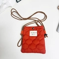 Detail of orange quilted nylon crossbody bag with rope strap and woven label - Orange