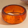 Detail view of thick resin bangle with translucent amber finish and smoky brown patterns - Amber Quicksand Texture / Amber Brown