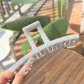 Cream-colored square hollow hair claw clip with golden spring held in hand - Greek-letter Shaped Extra Large Butterfly Buckle / Cement Grey (Approx 13.5cm)