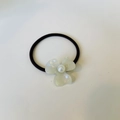 Detailed macro view of pearlescent flower hair tie with pearl center on black elastic band - White Mermaid