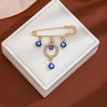 Detailed view of gold safety pin brooch with blue evil eye charms and rhinestones - Rhinestone Circle Style (Z105-2)