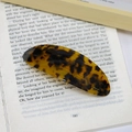Elegante fermaglio per capelli ovale in acetato tartarugato su una pagina di libro - Tortoise