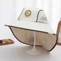 Detailed close-up of side mesh panels and round badge on large brim kids sun hat - 54cm (3-8 Years) / Beige