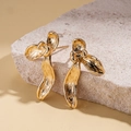 Detailed view of golden leaf-shaped earrings with hand-hammered texture on stone surface - Gold