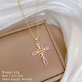 Dettaglio della collana a croce con zircone rosa e perla su una scatola beige - Stile Croce Con Perle e Zirconia Rosa (H136)