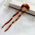 Elegante U-vormige haarspeld met schildpadpatroon op een witte stoffen achtergrond - Bruin