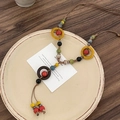Detalle de collar bohemio artesanal con cuentas de madera coloridas y borlas tejidas a mano - Multicolor