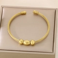 Detailed view of golden twisted steel wire bangle with polished beads in a jewelry box - Three Beads Decoration Style (KB187908-XY) / Gold