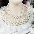 Detailed view of elegant multi-layer pearl necklace with clear acrylic accents on white lace - Multi-Layer Fashion Statement Pearl Necklace