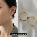 Detailed view of 4cm gold oval hoop earrings with twisted texture on silk background - 49# Silver Earring Post - Gold - Medium