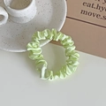 Light green satin scrunchie with glossy pleated texture on a white decorative plate - Light Green