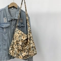 Close-up of floral pattern canvas tote bag hanging on a denim jacket and wood hanger - Yellow Floral