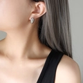 Minimalistische silberne ovale Ohrstecker mit poliertem Metallic-Finish am Modell - Stahlfarbe