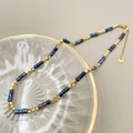 Détail du collier de perles avec acier doré et cylindres en marbre bleu sur plateau - Tz-n0543-02-bleu
