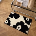 Plush black and white floral bathroom mat on wooden floor with modern aesthetic - Flowery Years