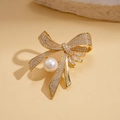 Detailed view of a gold bow brooch with micro-pave zircons and a large round white pearl - Gold-Bowknot